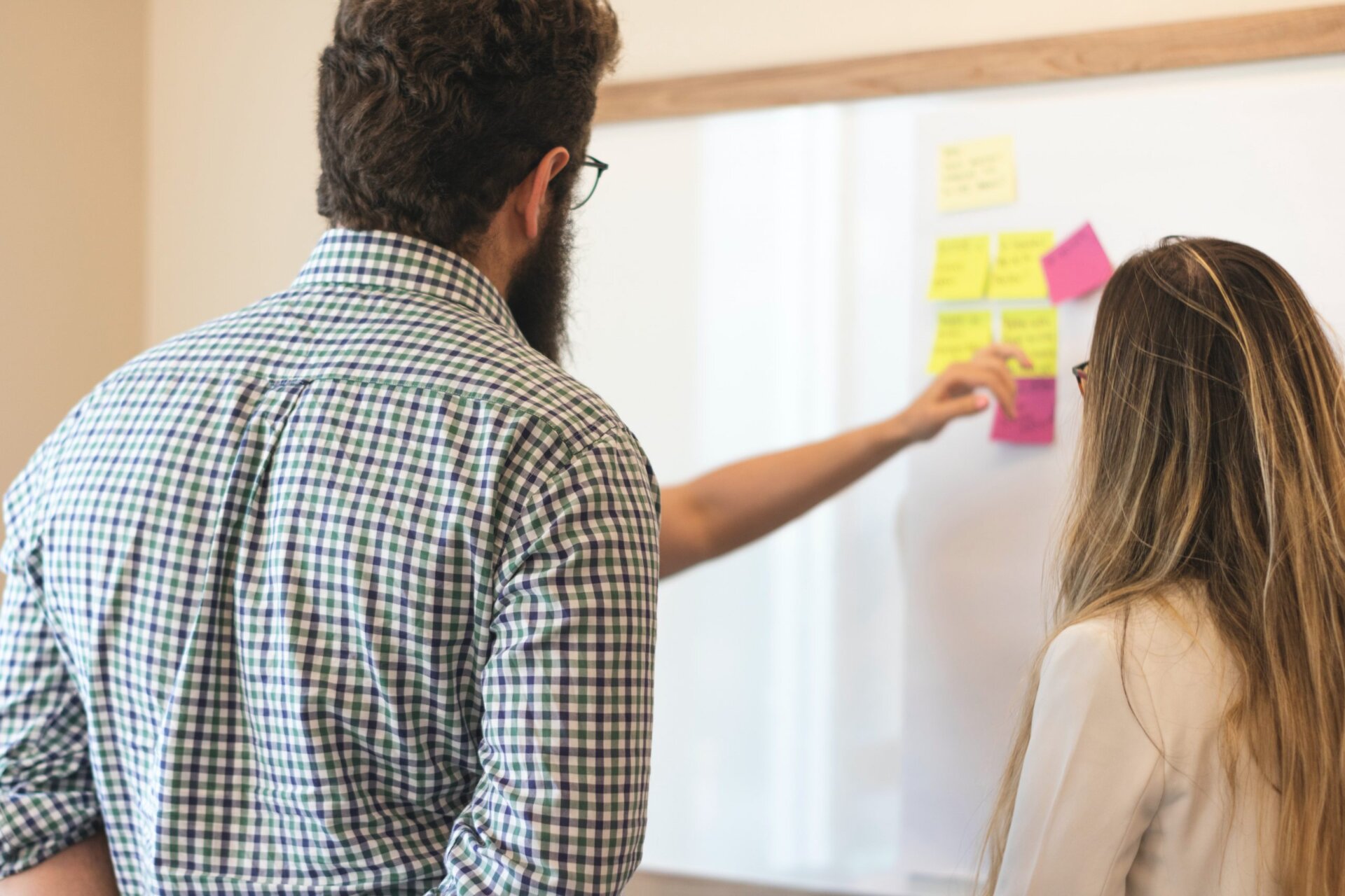 Adults looking at post it note ideas on white board