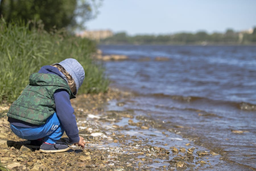 Kid playing at the shore of a river