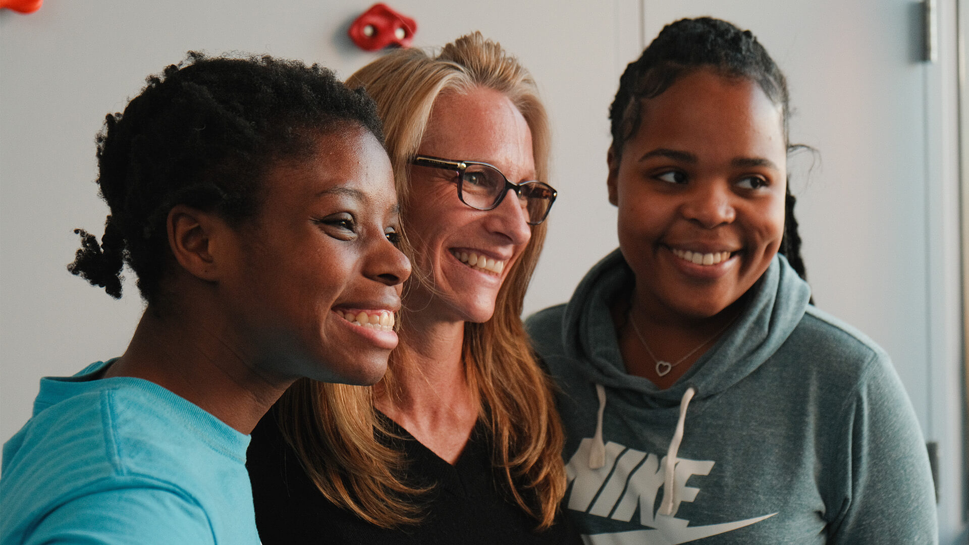 Three smiling caregivers in a supportive living environment.