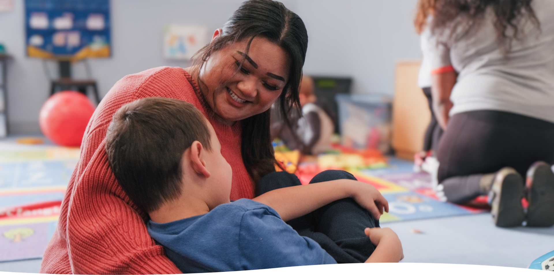 Woman smiling at child in a colorful playroom, creating a warm and friendly atmosphere.