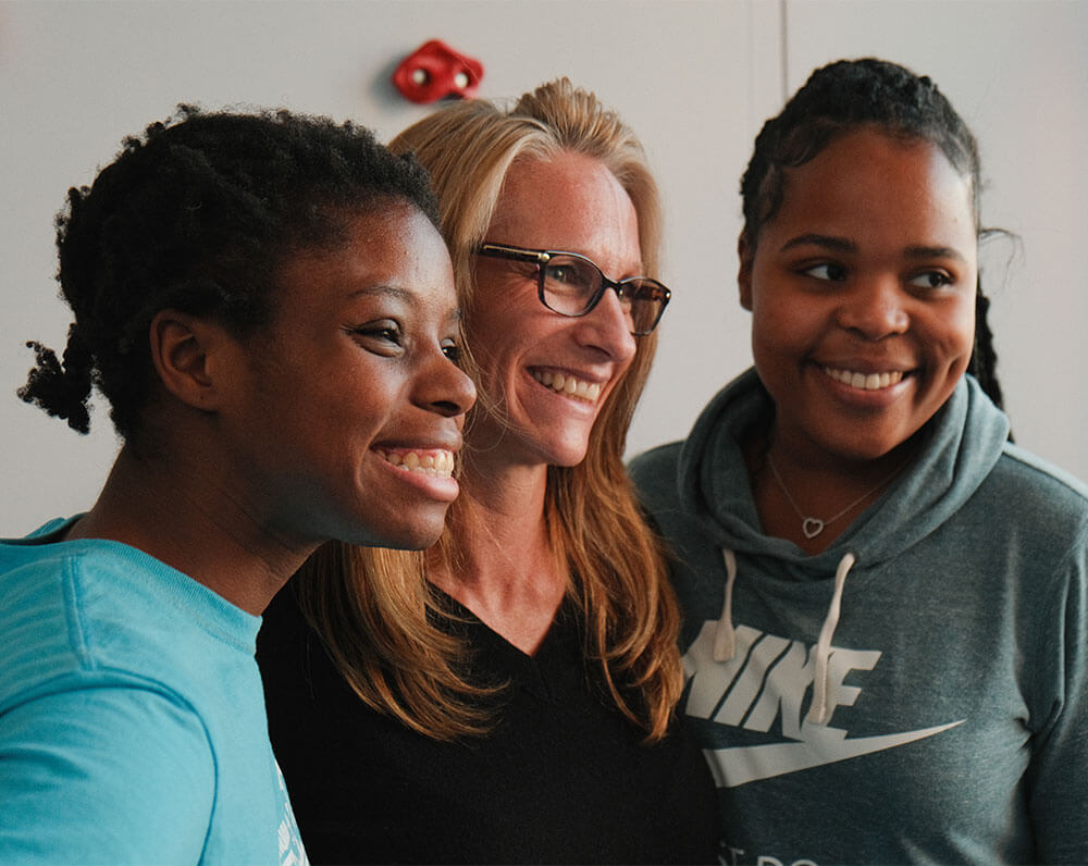 Three smiling caregivers in a supportive living environment.