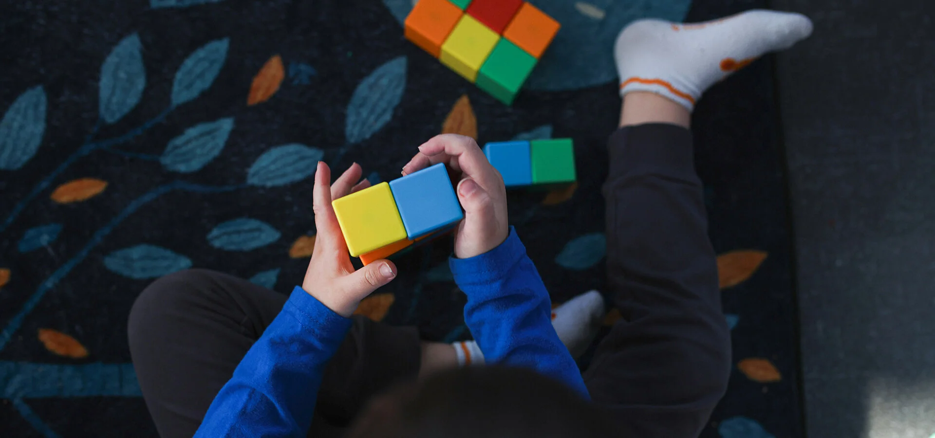 Small child playing with a variety of colorful blocks