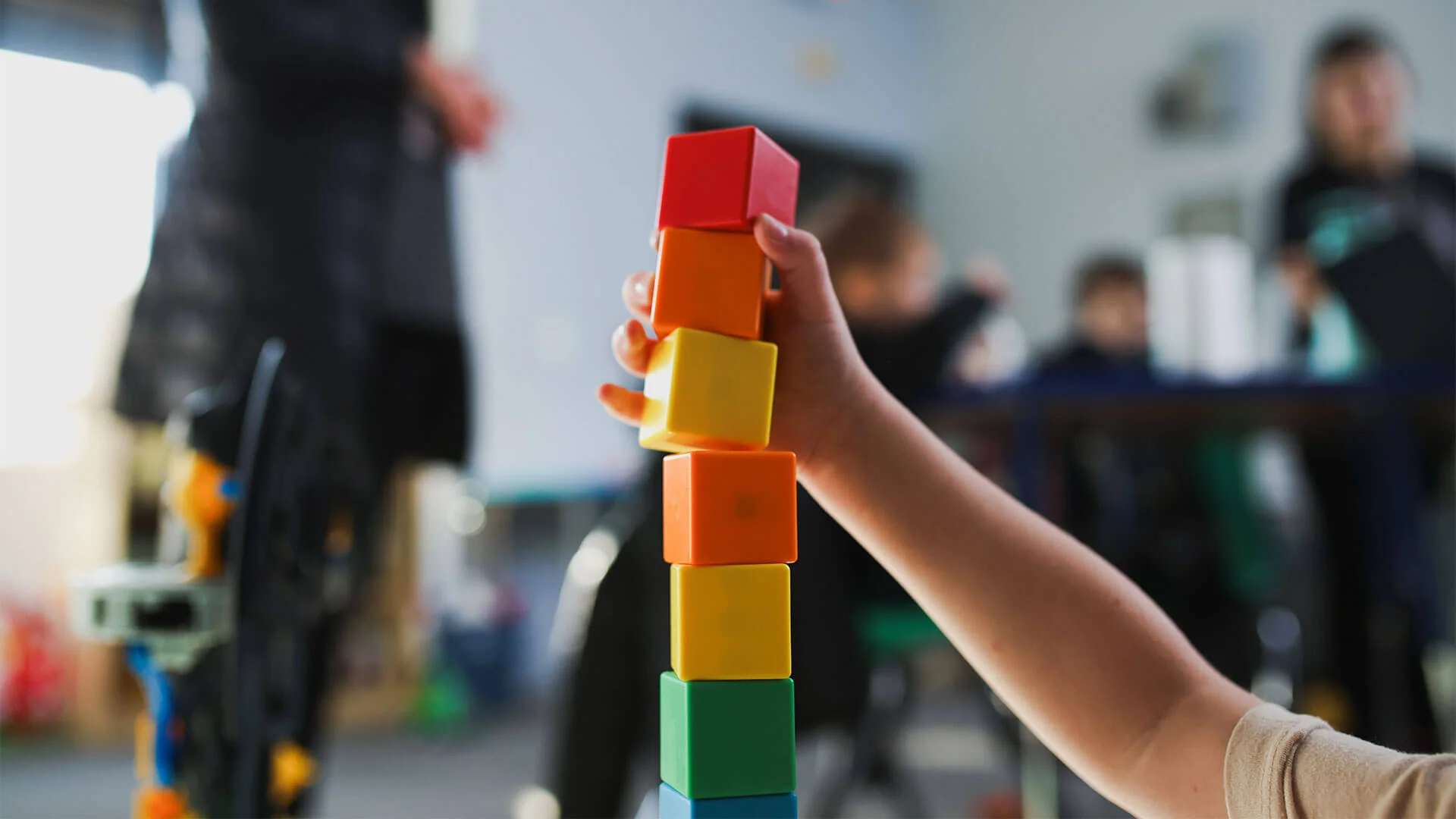 Childs hand stacking colorful blocks in a playful learning environment.