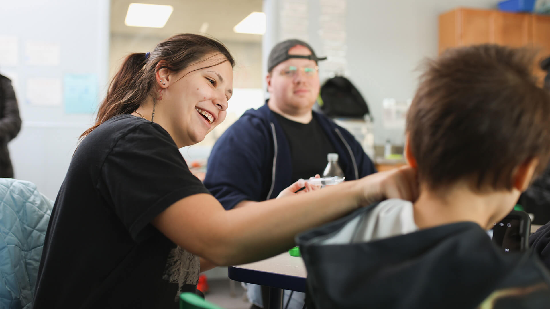 Woman smiling at a child during an activity session in a community center room.