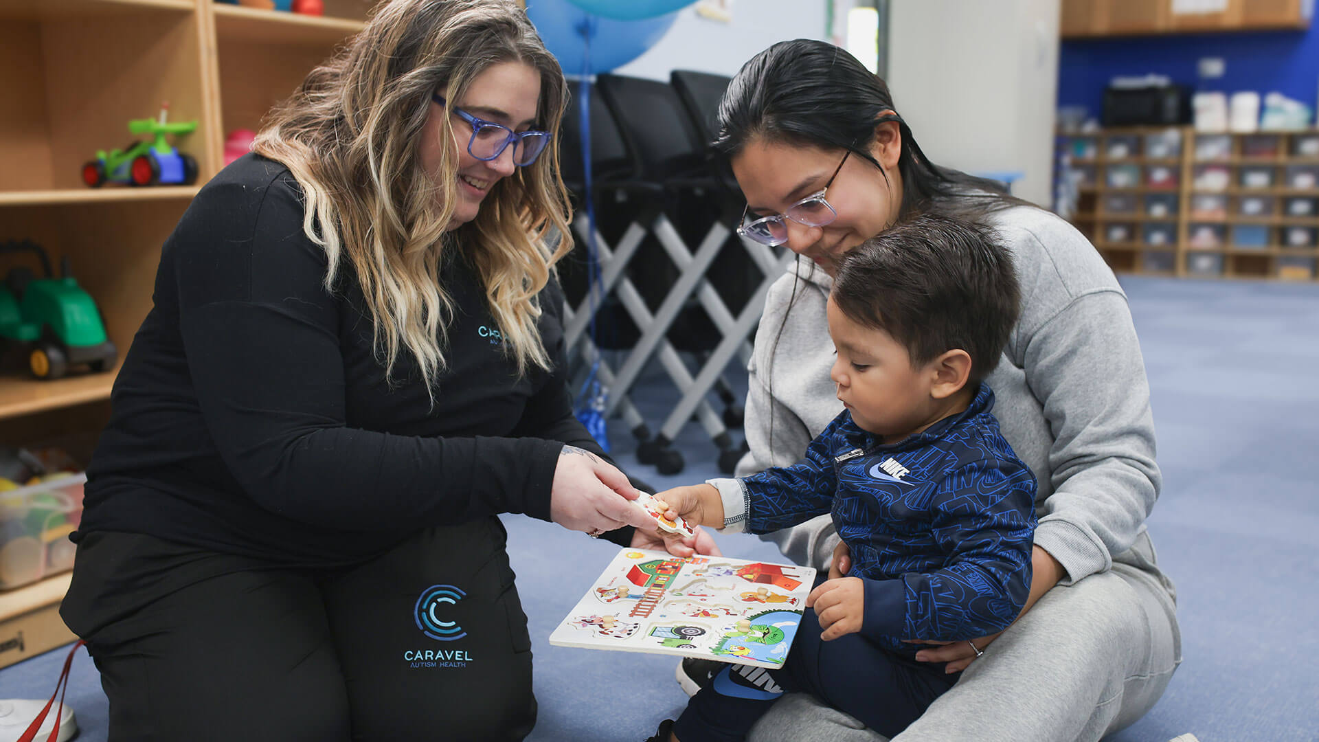 Caregiver engages child with puzzle activity in a colorful playroom setting.